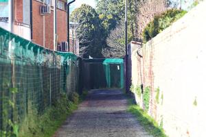 Path between a fence and a brick wall in a rural town photo