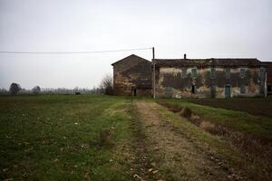 Abandoned farmhouse and a path in a field on a cloudy day in the italian countryside photo
