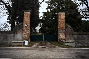 Gate and boundary wall of a country house by the edge of a road on a cloudy day photo