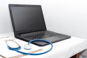 medical review chart next to a stethoscope next to a laptop with copy space. webinar concept of health and wellness and online medical consultation. photo