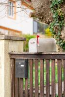 View of two different mailboxes installed on the fence of a private house photo
