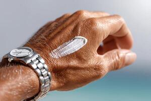 Applying sunscreen on a hand by the beach during a sunny day for skin protection photo