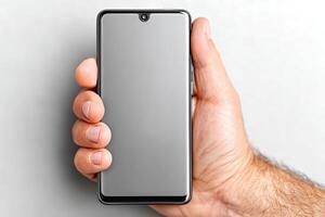 Hand holding a modern smartphone against a neutral background in a bright setting photo