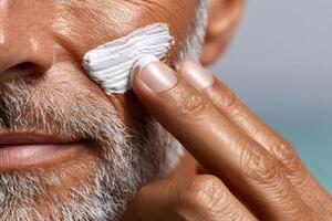 Man applying skincare cream to his face while outdoors on a sunny day near water photo