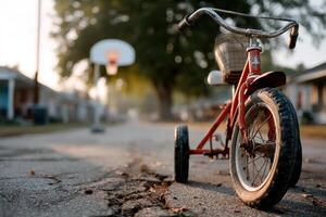 Old tricycle abandoned on a quiet street near a basketball hoop at sunset photo