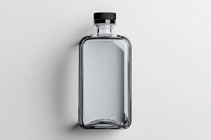 Transparent glass bottle with black cap resting on a light surface photo