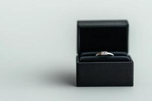 Elegant silver ring displayed in a plush black box on a soft grey background photo