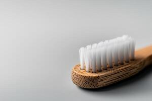 Eco-friendly toothbrush made of bamboo with soft bristles on a simple gray background photo
