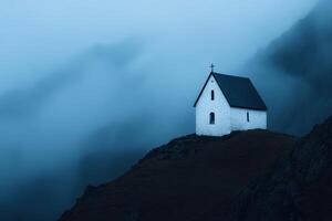 White church perched on a hilltop surrounded by misty mountains during twilight hours photo