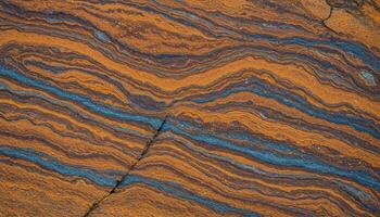 Sedimentary rock formation with orange and blue layered textures and wavy natural patterns photo