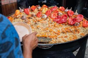 The cook puts hot delicious from the cauldron into a plastic plate. photo