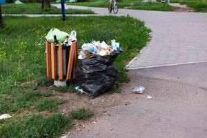 Overflowing green garbage bin in Surrey park clothe to Thames Path. photo