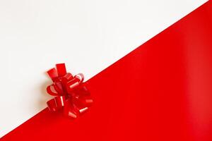 Red plastic bow on a red and white diagonal paper texture photo