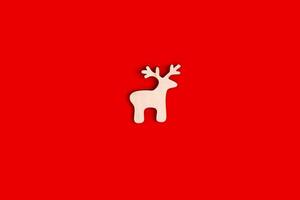 Deer figurine, flat, natural, unpainted wooden shape on a red background. photo