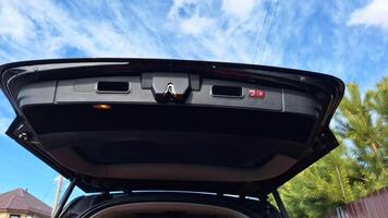 Open trunk lid of modern black suv under blue sky with clouds photo