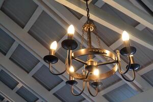 Rustic indoor chandelier with warm lights hanging from wooden ceiling photo