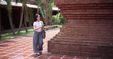 Handheld low angle view shot, Solo female tourist enjoying takes photos with mobile phone while strolling around, admiring the peaceful atmosphere and cultural beauty of the place. Leisure tourism video