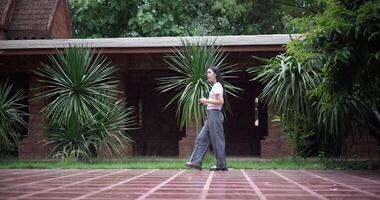Handheld side view shot, Solo female tourist enjoys taking photos with camera while taking a leisurely stroll amidst serene surroundings and the cultural richness of the place. Leisure tourism video