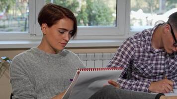 Cheerful college girl smiling at the camera while studying with a friend video