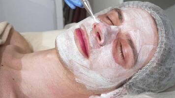 Relaxed happy handsome man enjoying a rejuvenating facial mask at a serene spa video