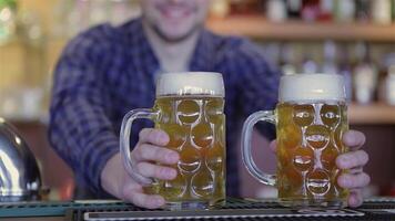 Bartender joyfully presenting two frothy beer mugs video