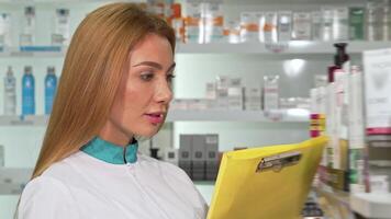 Cheerful female chemist smiling at the camera while diligently working in a vibrant drugstore video