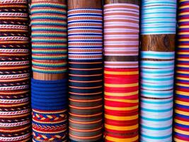 Colorful rolled fabric display with various patterns and textures photo