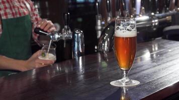 A refreshing glass of golden craft beer sparkles on the polished bar, while a skilled bartender pours another drink in the background. The inviting atmosphere captures the essence of relaxation and camaraderie, perfect for unwinding after a long day video