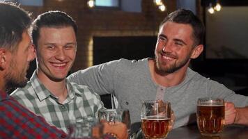 A lively gathering of handsome male friends clink their beer glasses, sharing laughter and camaraderie at a cozy pub. The warm ambiance, highlighted by soft lighting and rustic decor, enhances the joy of their post-work relaxation video