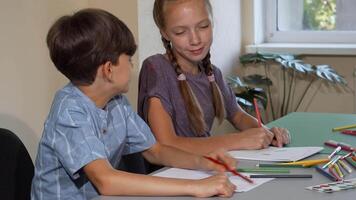 Two kids joyfully chatting and creating colorful drawings in art class video
