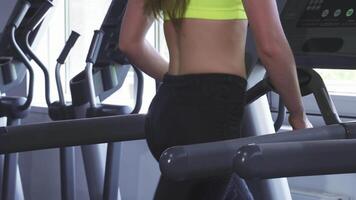 Dynamic close-up of a fit sportswoman showcasing her toned physique while running on a treadmill video