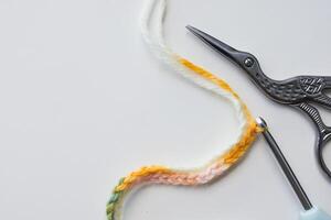 Crochet stitch pattern with colorful yarn, scissors, and hook on white background photo