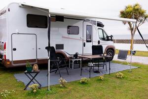 Modern rv camper setup with retractable awning at coastal campsite photo