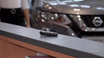 A stylish woman with elegant nails confidently retrieves car keys from a polished counter at a modern dealership. This vibrant scene captures the excitement of ownership, showcasing the moment of transition from shopper to proud car owner video