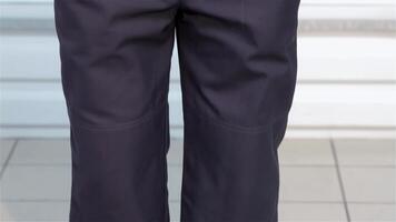 A focused view of a person wearing dark work pants, standing confidently next to a polished automotive vehicle. This image captures the essence of professionalism and dedication in the automotive industry, showcasing the blend of style and functionality video