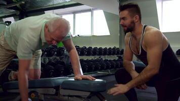 Trainer observing senior client performing exercises video