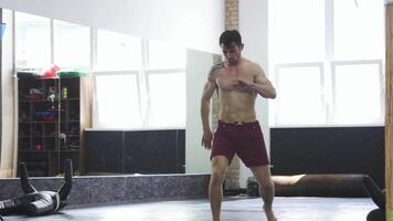 Dynamic full-length shot of a ripped MMA fighter executing high kicks in the gym video