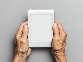 Elderly hands holding tablet with natural skin texture for technology and aging concepts photo