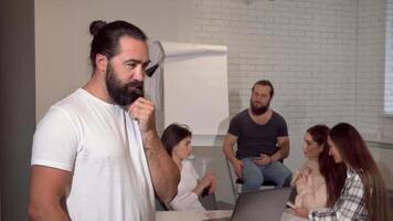 Confident bearded businessman smiling thoughtfully while leading a dynamic team video