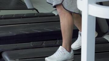 Focused man engaging with smartphone while walking on treadmill at gym video