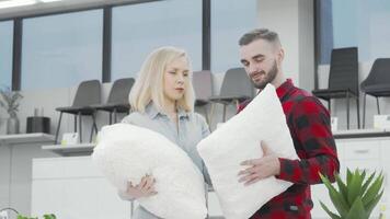 A joyful couple beams at the camera, cradling fluffy pillows as they explore a chic furnishings store. This delightful scene captures the essence of newlyweds joyfully curating their cozy apartment, surrounded by modern decor and vibrant greenery video