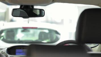 A young woman sits confidently in the driver's seat, adjusting the rearview mirror as she prepares for a test drive. The sleek interior of the car reflects modern technology and style, showcasing her excitement and determination to make a purchase video