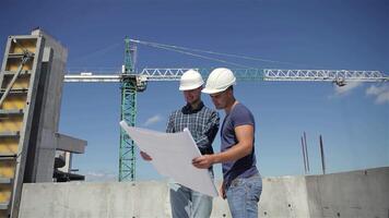 Construction manager points at the building plan with two builders engaged video