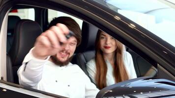 Happy couple proudly displaying car key through the window video