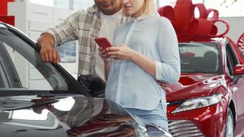 Young couple excitedly using smartphone while selecting their dream car video