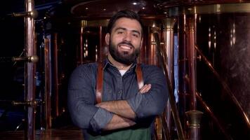 A confident bearded brewer in a stylish apron beams with pride, arms crossed, in his vibrant brewery. Surrounded by gleaming copper tanks and brewing equipment, he embodies the spirit of craft beer production and entrepreneurship video