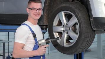 Smiling mechanic expertly wields a pneumatic wrench while fixing a wheel video