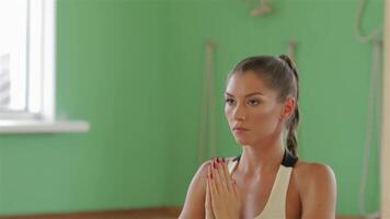 A focused young brunette girl elegantly practices yoga in a serene indoor setting, her arms raised in a tranquil pose. The vibrant green walls enhance the calming atmosphere, inviting a sense of peace and mindfulness as she embodies strength and grace video