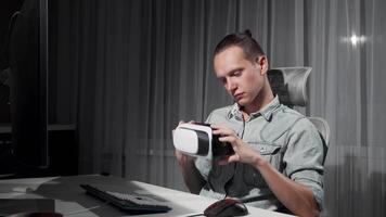 A handsome young man sits at his sleek desk, wearing virtual reality 3D glasses, fully absorbed in a captivating digital world. The dimly lit room enhances the excitement of his new adventure, showcasing the fusion of technology and imagination video