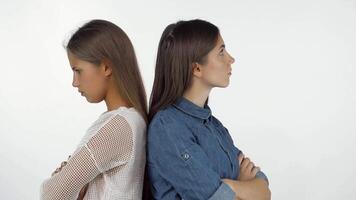 Two young women stand back to back, arms crossed and expressions filled with frustration, showcasing the tension after a quarrel. Their contrasting emotions highlight the complexities of friendship, as they navigate feelings of anger and disappointment video
